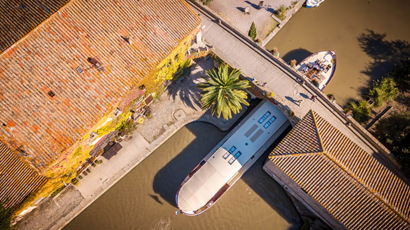 French Hotel Barge Roi Soleil on the Canal du Midi passing under the bridge at Le Somail