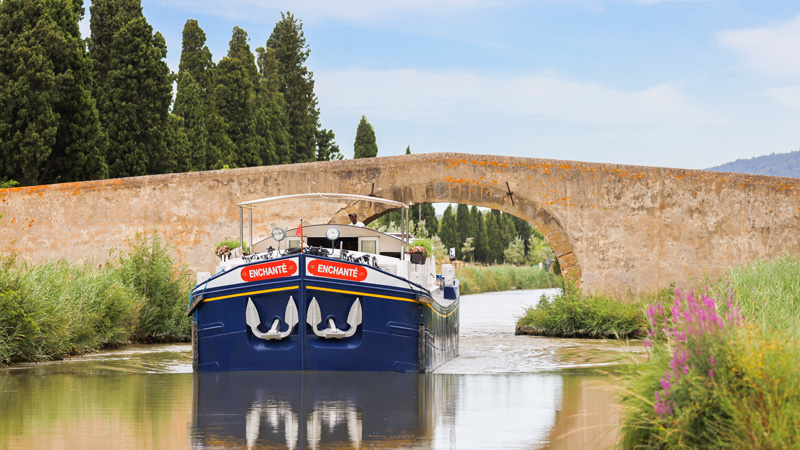 French Hotel Barge Enchante - leaving the bridge they just passed under on the Canal du Midi in southern France