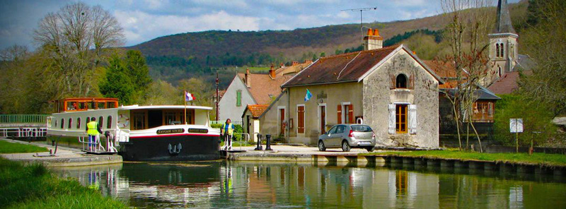 French Hotel Barge Savoir Vivre exits a lock on the Canal du Bourgogne in Burgundy France