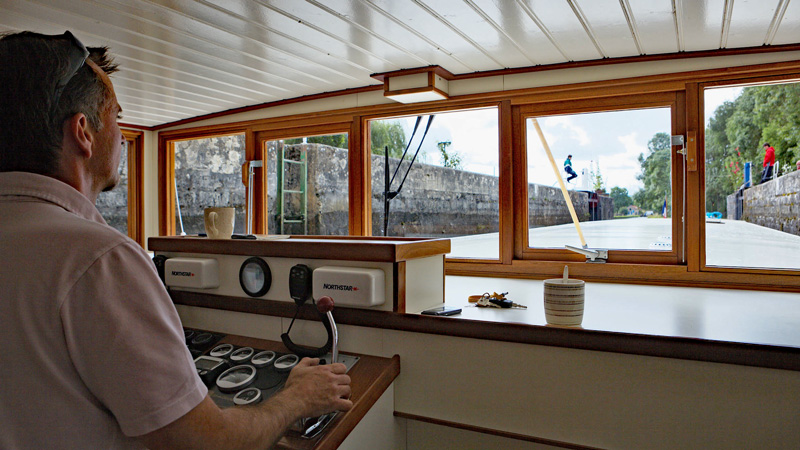 Captain Richard Megret at the helm in the wheelhouse of French Hotel Barge Savoir Vivre