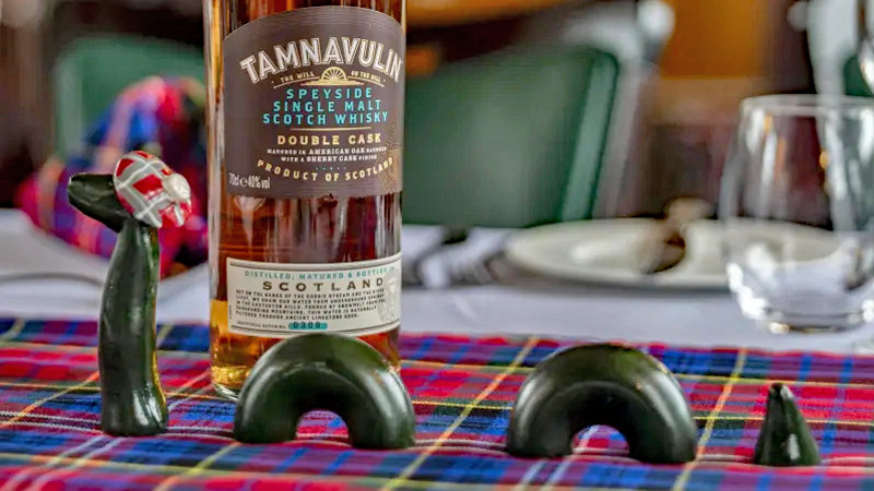 A Nessie sighting - Table piece with Nessie on a tartan table runner alongside a bottle of single malt Scotch whisky
