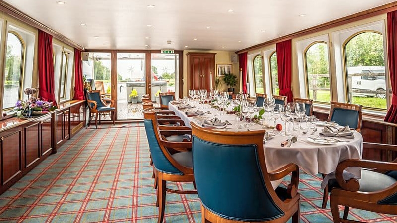Scottish Hotel Barge Spirit of Scotland - Dining table is set and ready for a meal. Panoramic windows adds to the spaciousness of the dining area