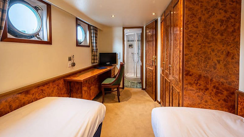 Scottish Hotel Barge Spirit of Scotland - Guest cabin with twin bed arrangement. Photo shows beds,  portholes, closets, and table top
