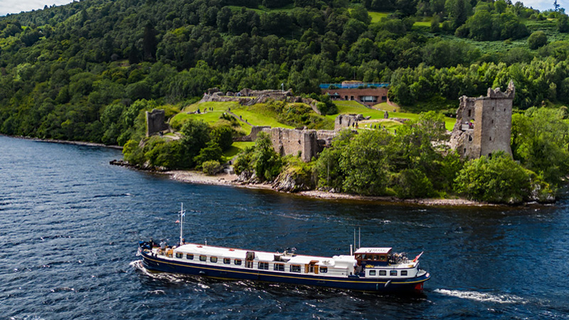 Scotland - Barge Scottish Highlander passing by Urquhart Castle. ew