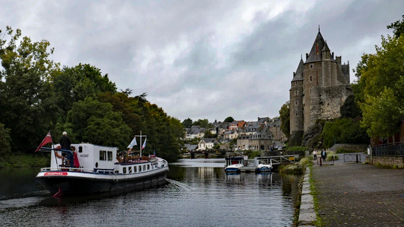 French Hotel Barge Nymphea cruising by the Château de Josselin in Brittany, France