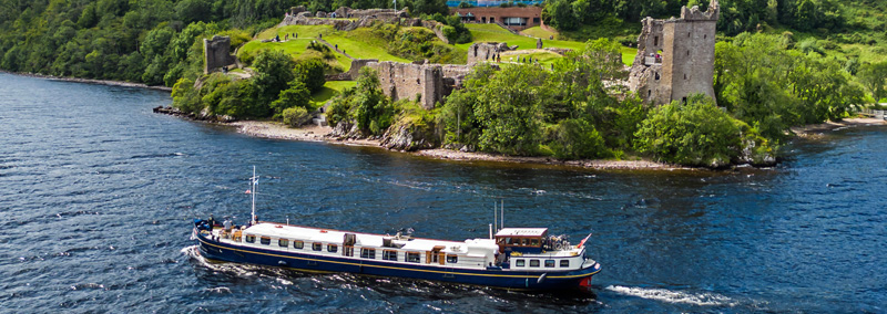 Header - Barging in Scotland. Scottish Highlander cruising past Urquhart castle.